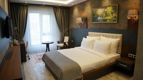 - une chambre avec un grand lit blanc et une fenêtre dans l'établissement Kahra Otel, à Amasya