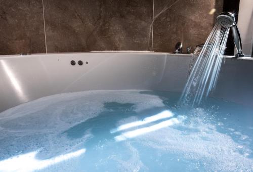 uma banheira cheia de água azul com um chuveiro em Complejo Enoturístico Finca La Estacada em Tarancón