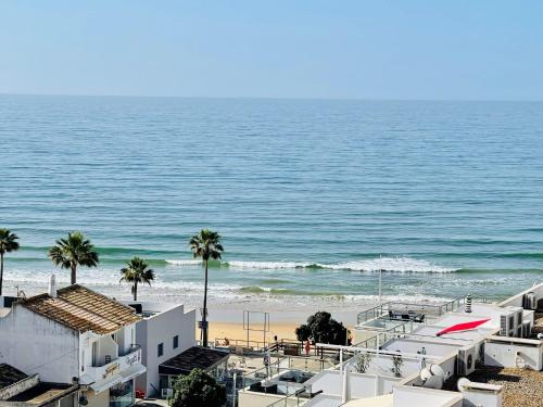 a view of a beach with palm trees and buildings at On The BEACH Stunning Apartment Albufeira Olhos de Água in Albufeira