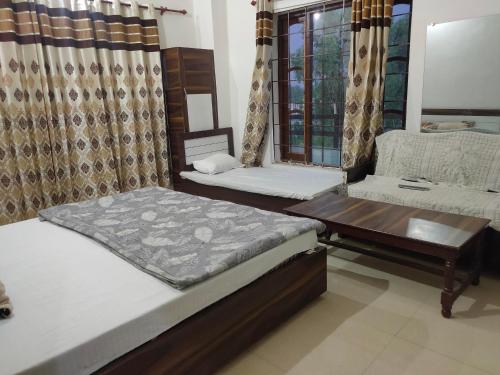 1 dormitorio con 2 camas, mesa y sofá en ARJUN GUEST HOUSE, en Pathankot