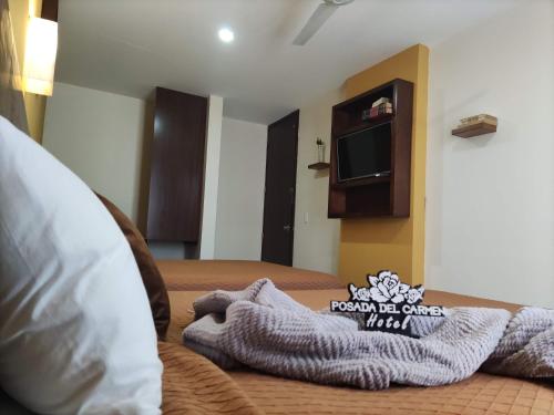 a hotel room with a blanket on a bed with a tv at Posada Del Carmen Aguascalientes in Aguascalientes