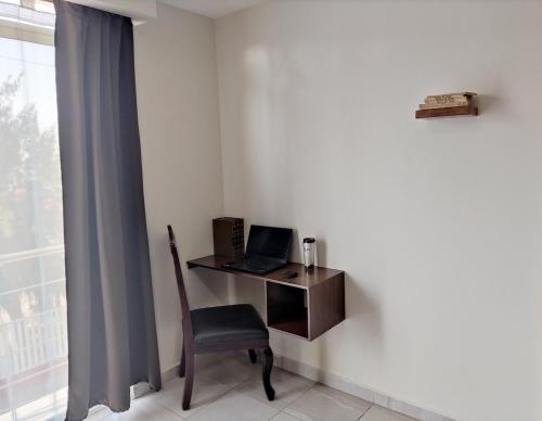 a desk with a laptop and a chair next to a window at Posada Del Carmen Aguascalientes in Aguascalientes