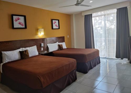 a hotel room with two beds and a window at Posada Del Carmen Aguascalientes in Aguascalientes