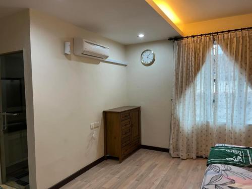 una camera da letto con un orologio sul muro e un comò di Rumah Armand Masjid Tanah Melaka 4BR Fully Aircond a Masjid Tanah