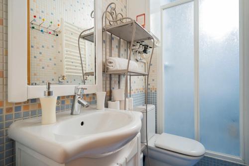 ein Badezimmer mit Waschbecken, Toilette und Spiegel in der Unterkunft Cosy Apartment Malasaña in Madrid