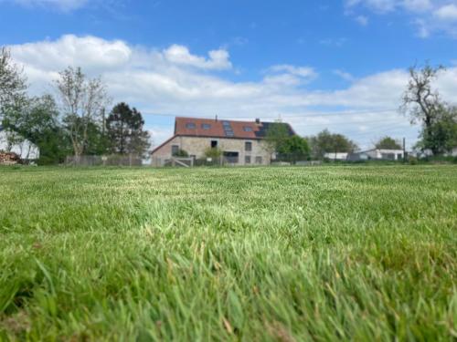 a field of green grass with a house in the background at La Souricière in Silenrieux