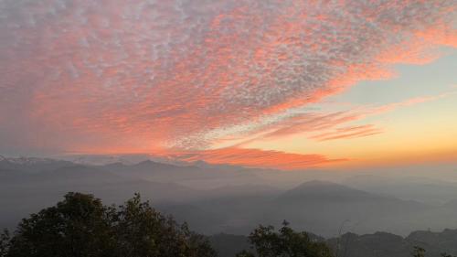 a sunset with a view of mountains and clouds at Hotel Pristine Himalaya in Pokhara