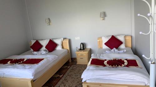 two beds in a room with red and white pillows at Hotel Pristine Himalaya in Pokhara