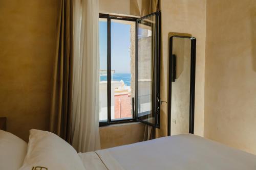 a bedroom with a window with a view of the ocean at BAYIT Charming Place in Polignano a Mare
