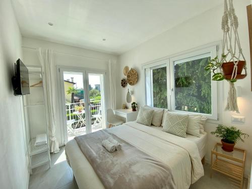 a white bedroom with a large bed and a window at Pathos Guest House in Quarto dʼAltino
