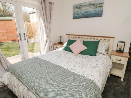 a bedroom with a bed with green and pink pillows at High Tide House in Craster