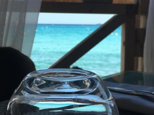 a glass bottle sitting on a table with a view of the ocean at Restaurant - Chambres d'Hôtes Terra Bella Lecci in Porto-Vecchio