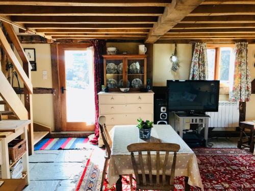 uma sala de estar com uma mesa e uma televisão em The Cottage, Winley Farm em Bromyard