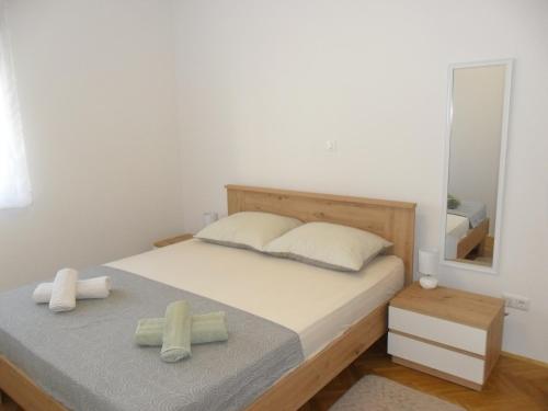 une chambre avec un lit avec deux oreillers et un miroir dans l'établissement APARTMAN LJUBICA, à Trogir