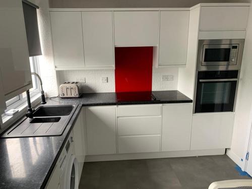 a kitchen with white cabinets and a red counter top at Double room with private bathroom in Basingstoke in Basingstoke