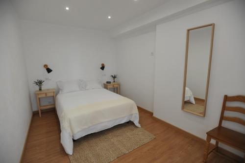 a white bedroom with a bed and a mirror at Lagos Central Apartments Ap 10 in Lagos