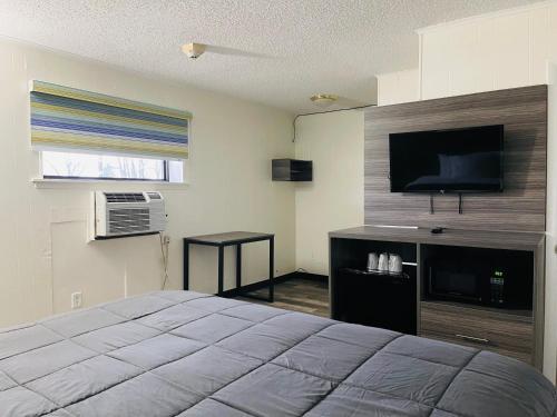 1 dormitorio con 1 cama y TV de pantalla plana en Crown Inn Motel, en Linden
