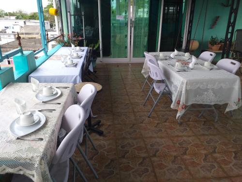 a row of tables in a restaurant with white linens at Tyvabro Guesthouse in Mahébourg
