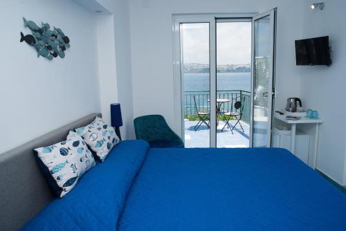 a bedroom with a blue bed and a balcony at Punta Lingua Relais- Room 1 Sunrise Terrace in Procida