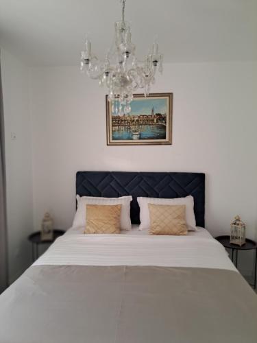- une chambre avec un grand lit blanc et un lustre dans l'établissement Apartman Stella Maris, à Ljubuški