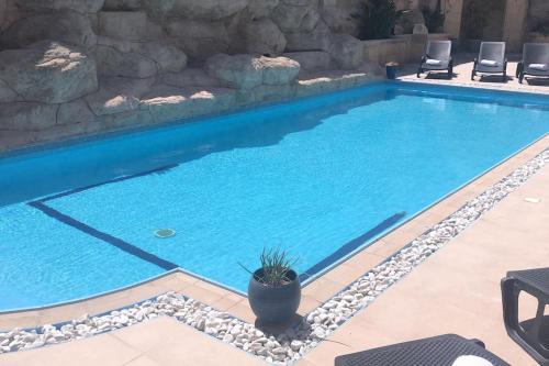 a large swimming pool with a stone wall at Velver Mansion, Malta - Luxury Villa with Pool in Naxxar