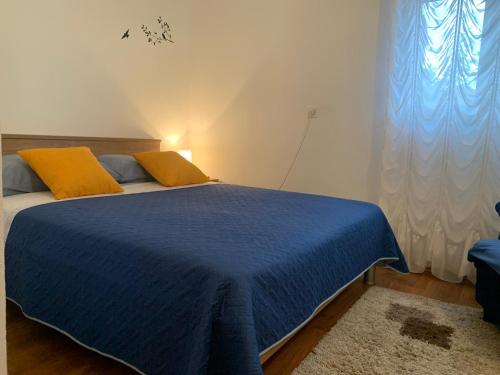 a bedroom with a blue bed with yellow pillows at Apartman ABO*** in Komin