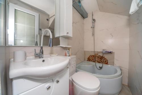 a white bathroom with a sink and a toilet at La Costa Apartments in Bar