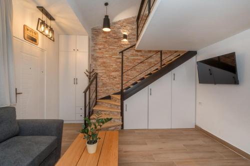 a living room with a staircase and a brick wall at La Costa Apartments in Bar