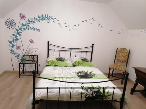 a bedroom with a bed with green sheets and flowers on the wall at Chez Nicole in Ballon