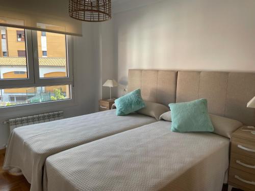 a bedroom with a large bed with two blue pillows at Apartamento Turistico Mirador de Valdellera I in Posada de Llanes