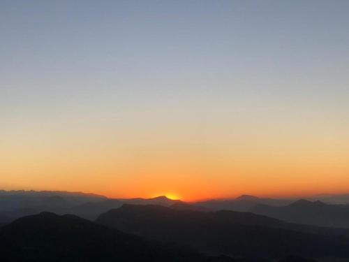 a sunset over a mountain range with the sun setting at Hotel Pristine Himalaya in Pokhara