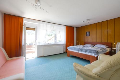 a bedroom with a bed and a couch and a window at Apartments and Rooms Banić in Kranjska Gora