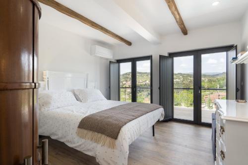 a bedroom with a white bed and large windows at Quinta De Fundevila -quinta privada in Cabeceiras de Basto