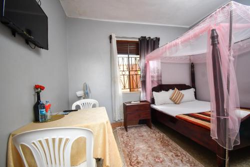 1 dormitorio con cama con dosel, mesa y sillas en Jinja Grand Hotel en Jinja