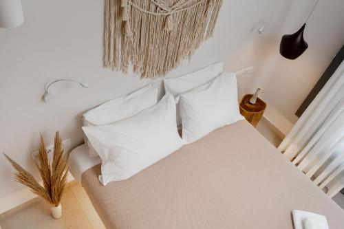 a bedroom with a white bed with white pillows at Melidron Hotel & Suites in Agios Prokopios