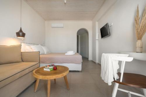 a living room with a couch and a bed and a table at Melidron Hotel & Suites in Agios Prokopios