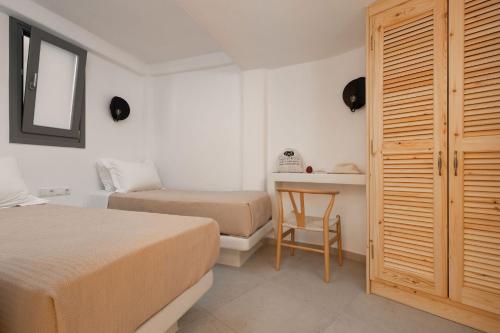 a bedroom with two beds and a desk and a chair at Melidron Hotel & Suites in Agios Prokopios