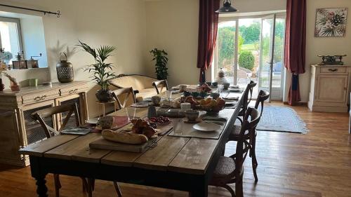 a long wooden table with chairs in a living room at TENDANCE CAMPAGNE Chambre d'hôtes in Marillac