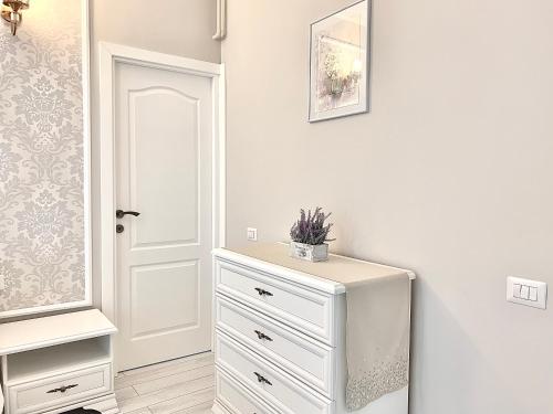 a white bedroom with a dresser and a door at Summer apartments in Eforie Nord