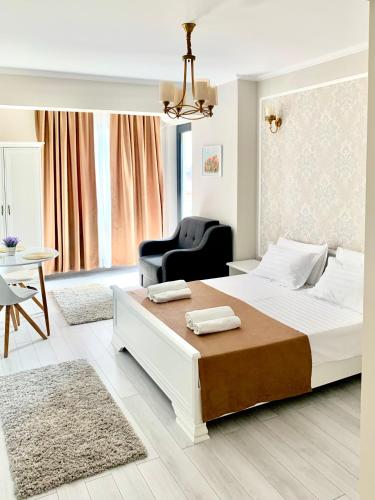 a white bedroom with a large bed and a chair at Summer apartments in Eforie Nord