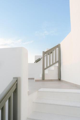 a staircase in a white room with a bench at Melidron Hotel & Suites in Agios Prokopios