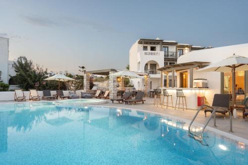 a swimming pool with chairs and umbrellas next to a building at Melidron Hotel & Suites in Agios Prokopios