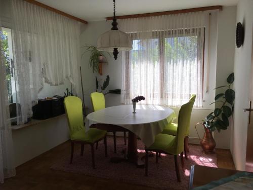 a dining room with a table and green chairs at Ferienwohnung Immenstaad in Immenstaad am Bodensee