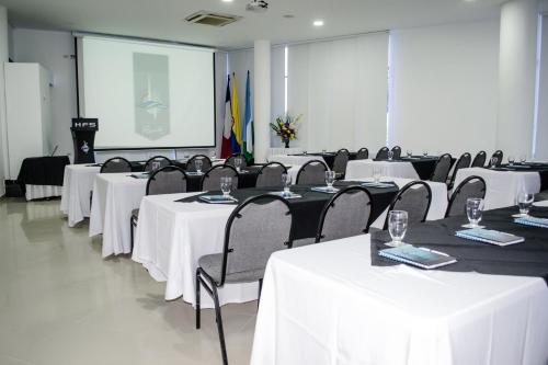 a conference room with white tables and chairs and a screen at Hotel Florida Sinú in Montería