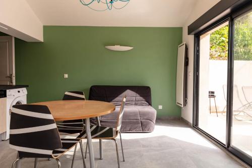 a dining room with green walls and a table and chairs at LA MAISONNETTE in Thueyts