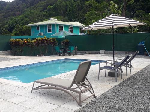 a swimming pool with two chairs and an umbrella at Amazon Villas in Soufrière