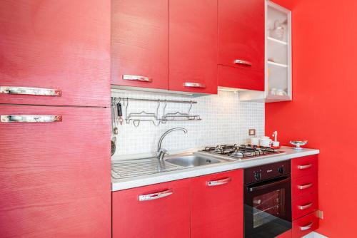 a red kitchen with a sink and red cabinets at Castello Normanno Modern Sea View Apartment in Aci Castello