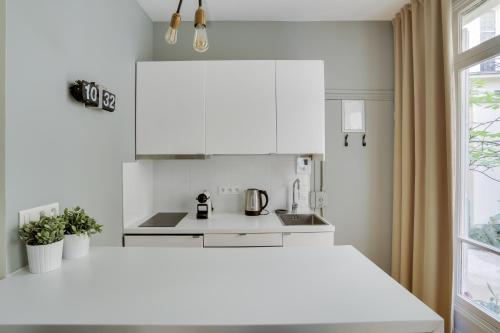 une cuisine blanche avec des armoires blanches et une fenêtre dans l'établissement Charmant studio au coeur de Paris pour 2 personnes by Weekome, à Paris