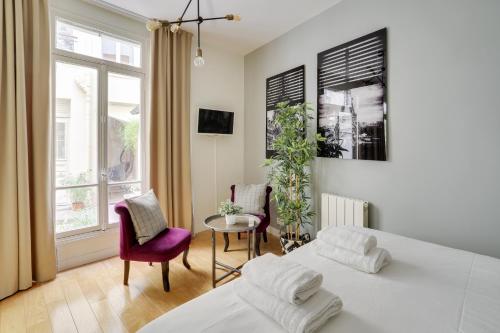 une chambre avec deux lits et une table et des chaises dans l'établissement Charmant studio au coeur de Paris pour 2 personnes by Weekome, à Paris