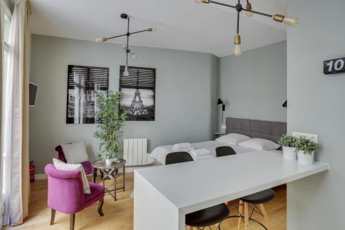 une cuisine et un salon avec une table et des chaises blanches dans l'établissement Charmant studio au coeur de Paris pour 2 personnes by Weekome, à Paris